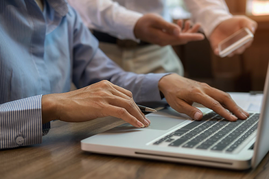 Immagine di un team che collabora mostrando un progetto su un laptop, illustrando supporto e lavoro condiviso con il cliente